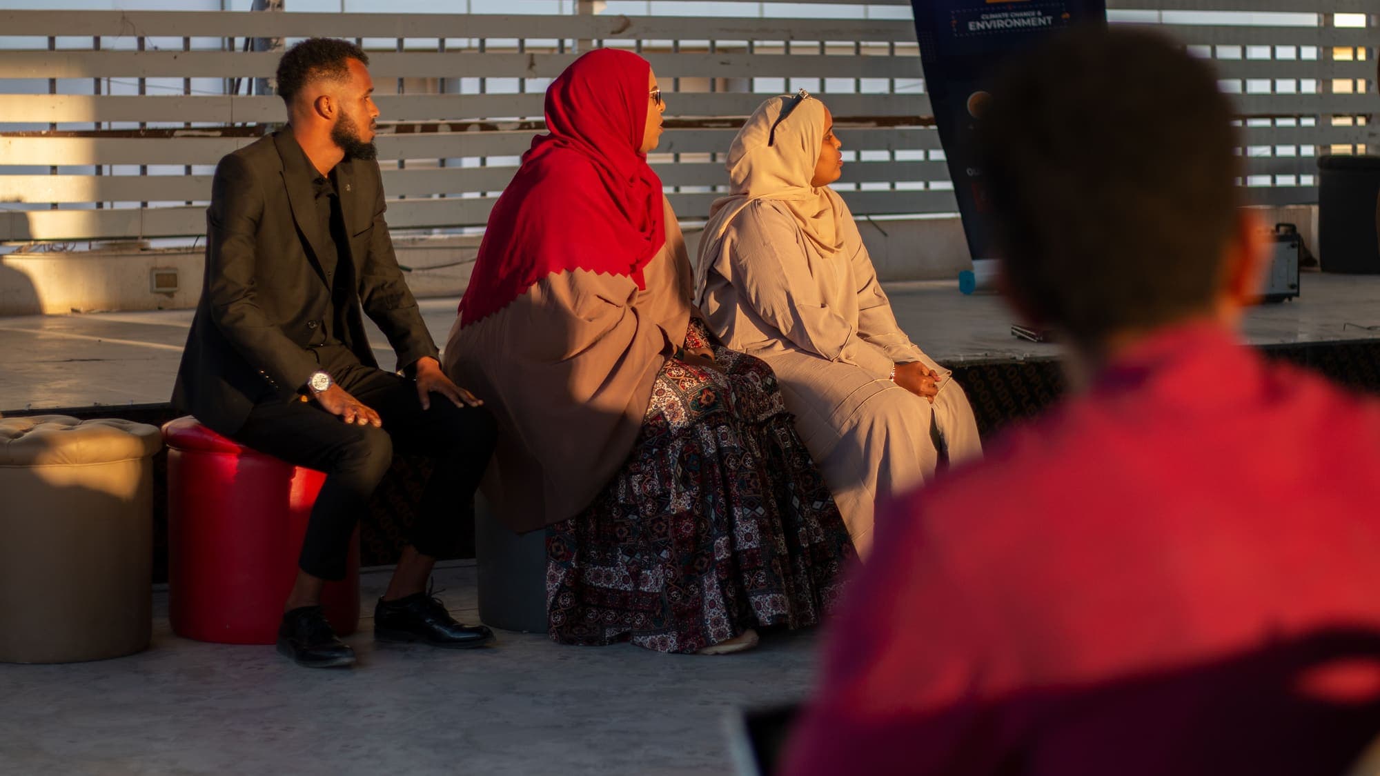 Three people sit talking in the evening light
